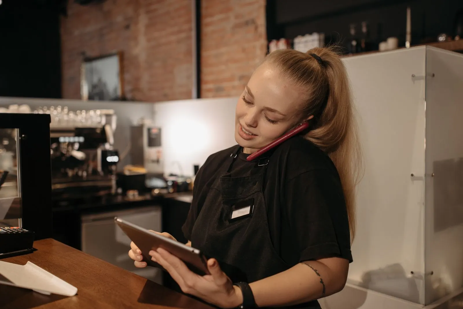 A manager takes an order by phone while logging it on a tablet